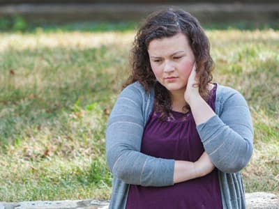 Woman standing outside with hand on neck thinking about calling depression hotline