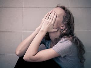 Woman with anorexia covering face with hands