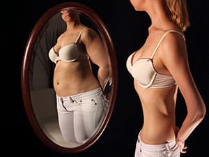 Woman with anorexia looking in mirror