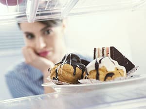 Girl staring at sweets in the refrigerator