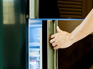 man opening fridge at night