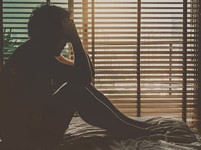 Depressed man holding his head in his bedroom