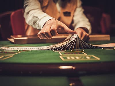 Dealer with deck of cards behind table